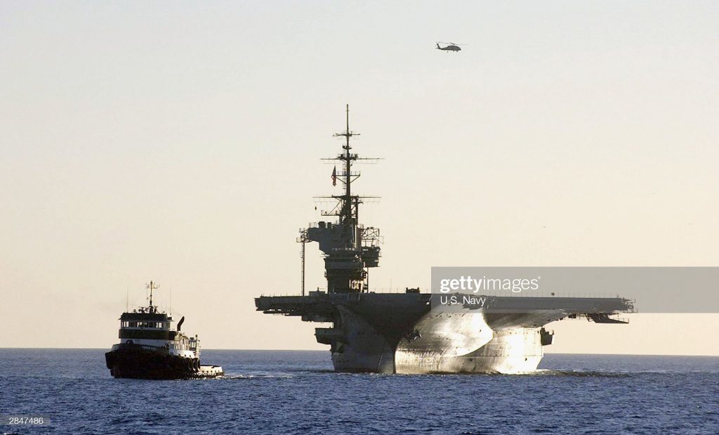 Photo of tugboat towing an aircraft carrier